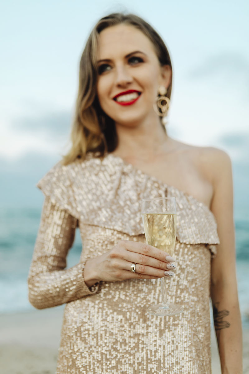 一个穿着金色裙子的女人在沙滩上喝着香槟