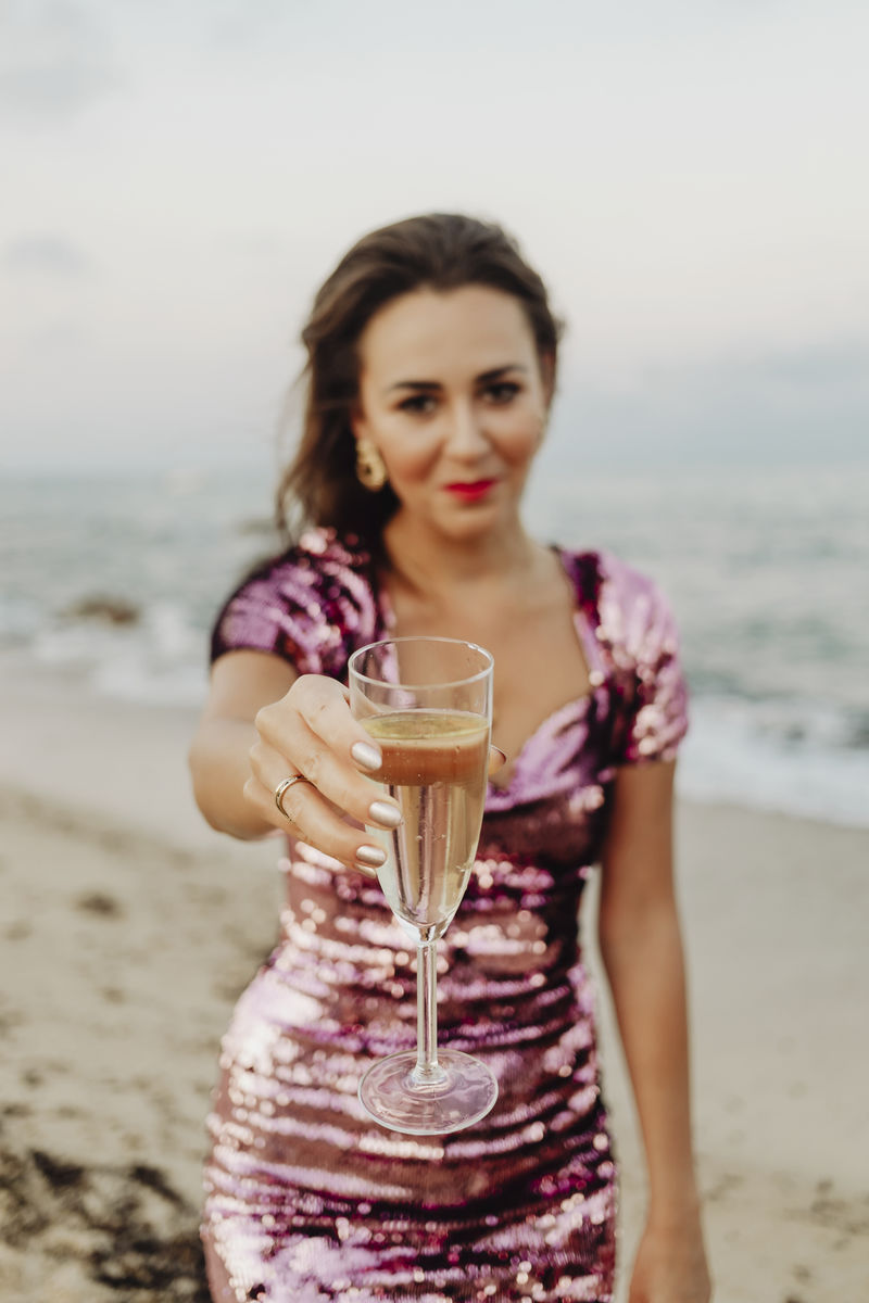 穿着粉红色裙子的女人在海滩上喝着香槟