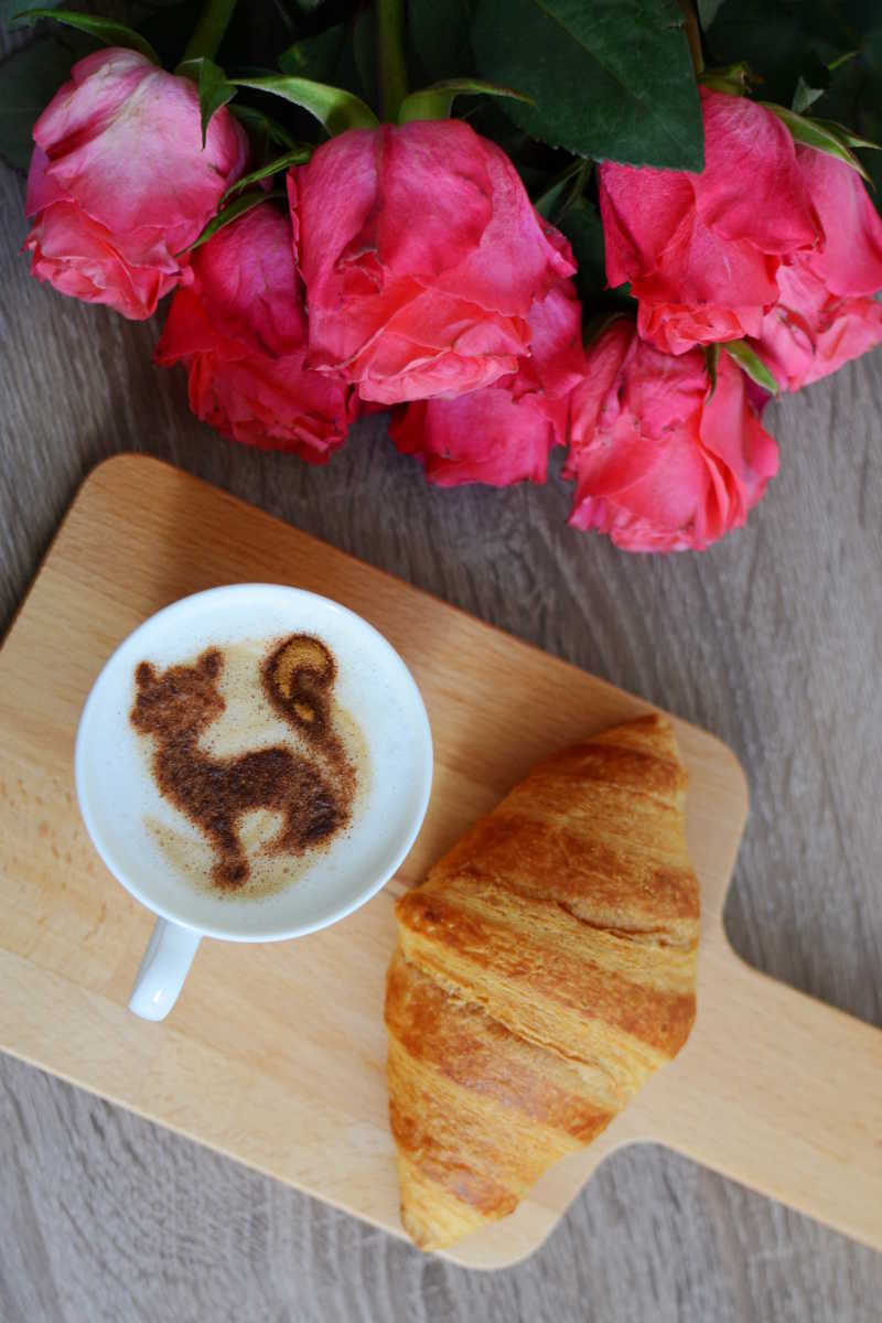 一杯咖啡与面包和红色花朵