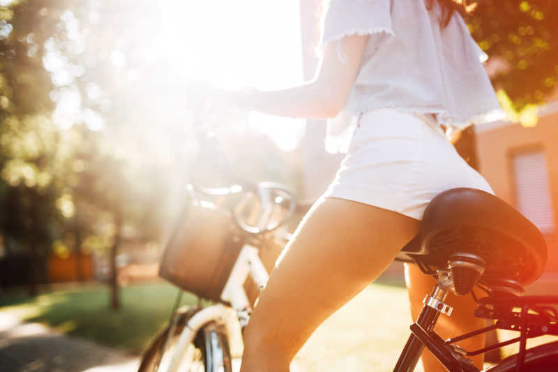 阳光下骑自行车的年轻女孩局部