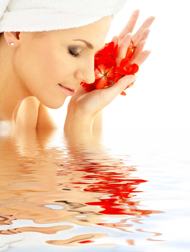 在水中可爱的女人带着红色的花瓣