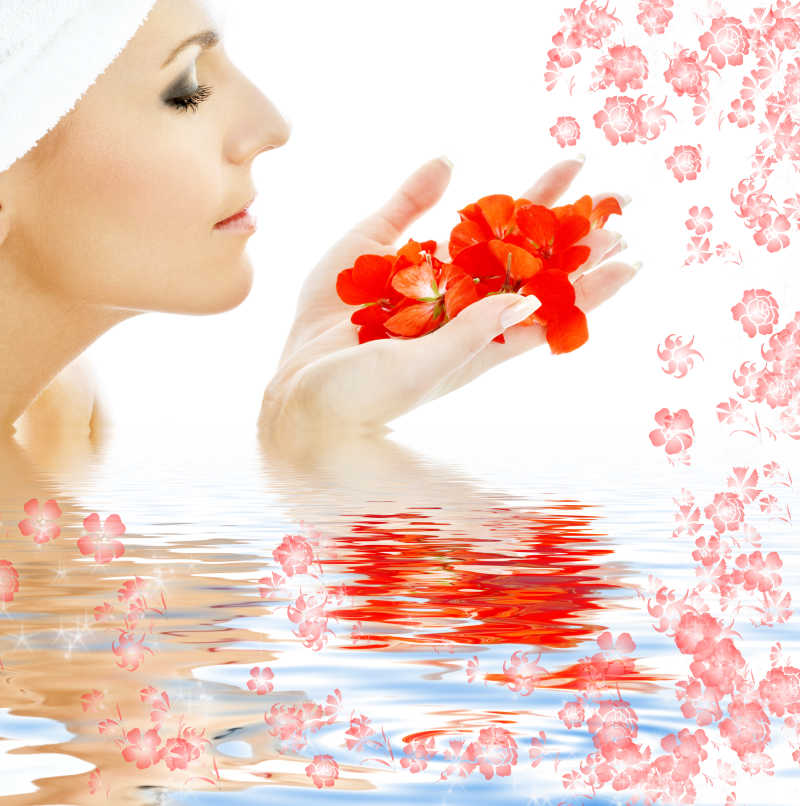 可爱的女人在水中带着红色的花瓣
