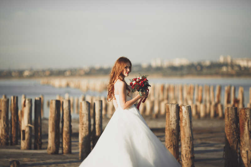 穿着白色礼服站在海边的新娘