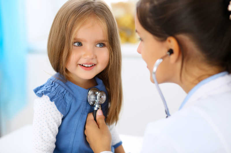 女医生用听诊器检查一个小女孩
