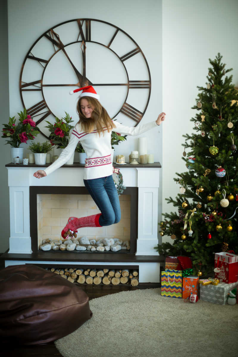 在圣诞树旁边跳起来的少女