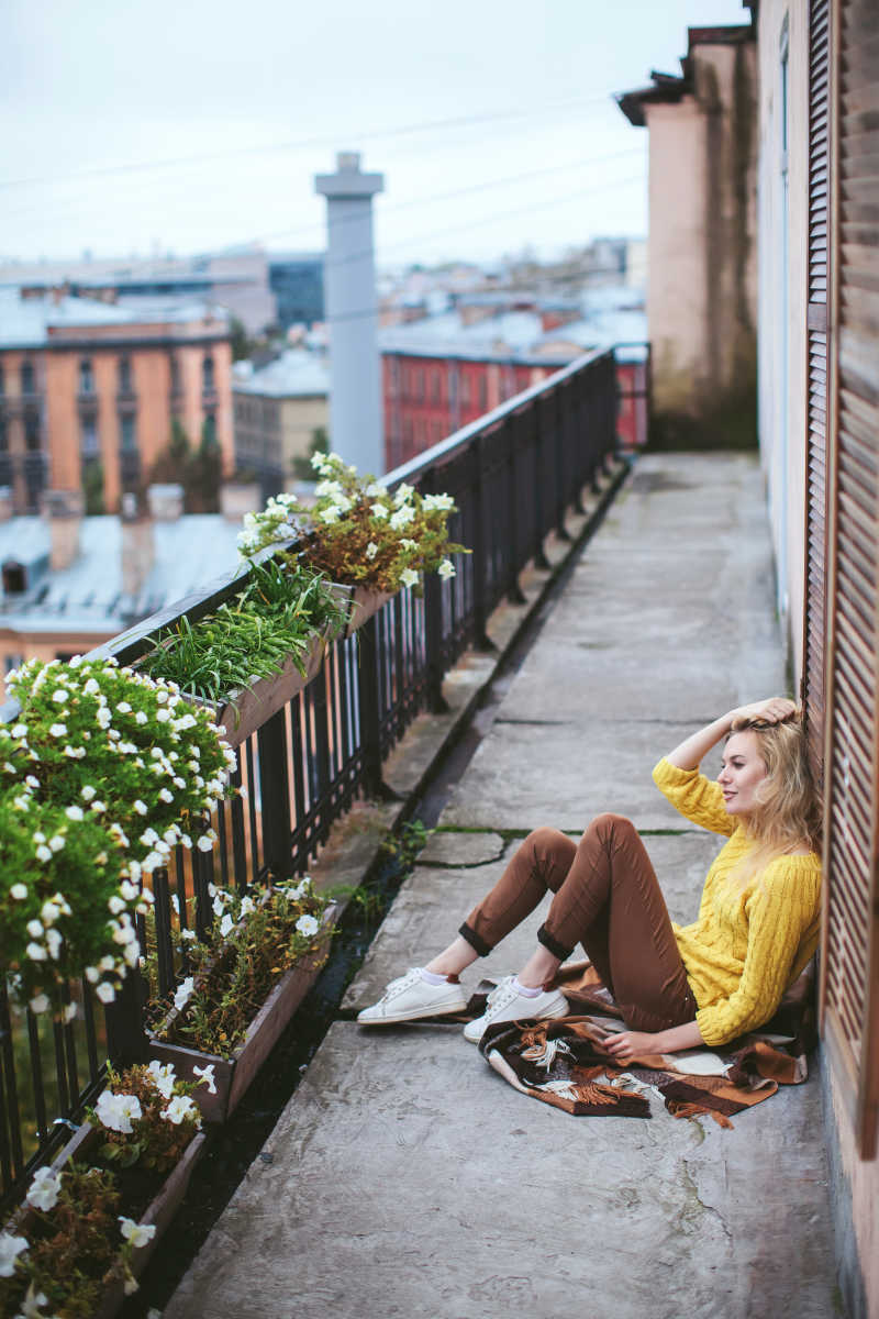 建筑背景下坐在阳台上的金发美女