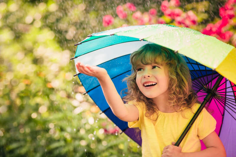 撑着伞的孩子用手触摸雨水