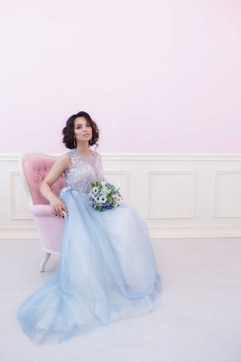 坐在粉红色椅子上的蓝色纱裙新娘
