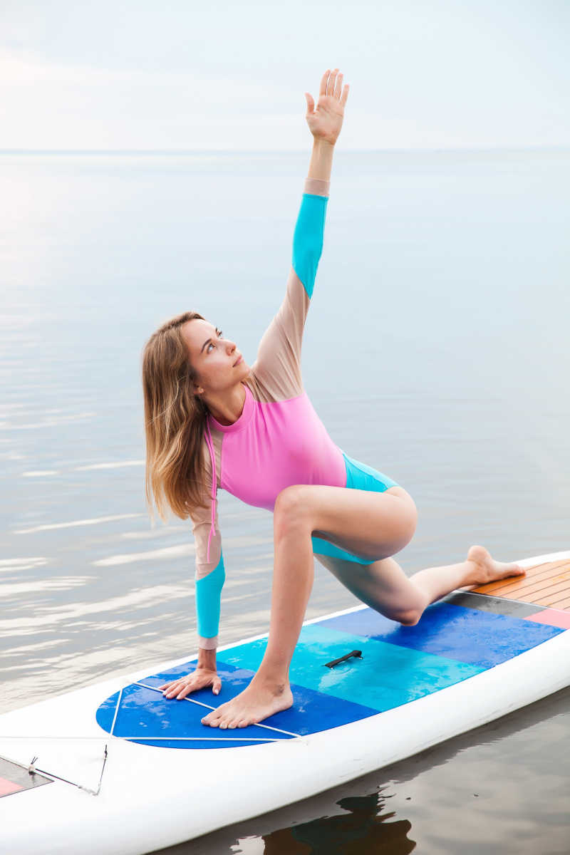 在水面瑜伽板上做瑜伽的年轻女子