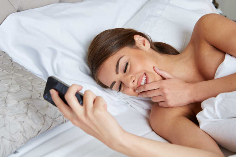 在床上玩手机微笑的女人