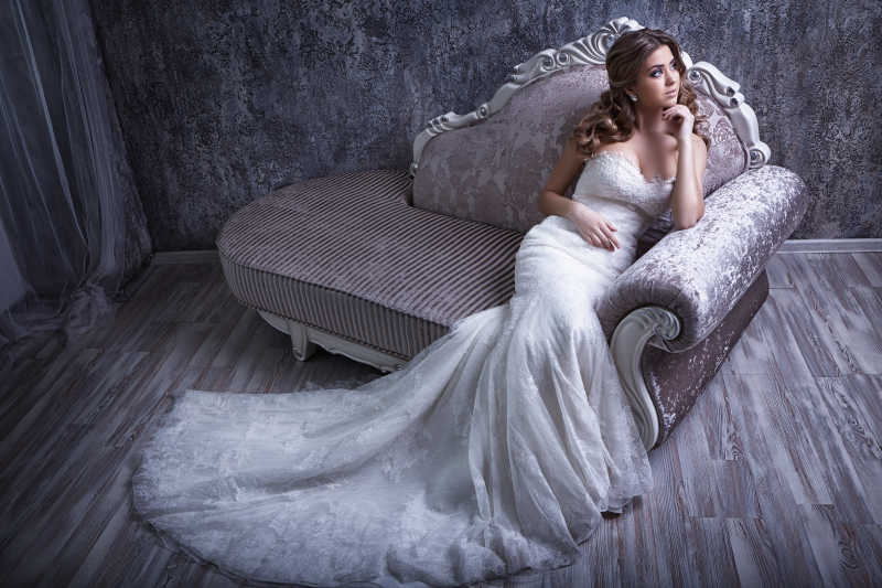 年轻漂亮的新娘坐在古董沙发上