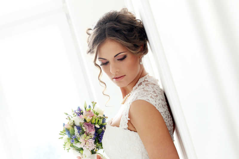 拿着花束穿着白色婚纱的美丽的新娘