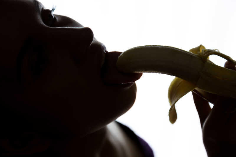 黑白背景中的吮吸香蕉的美女