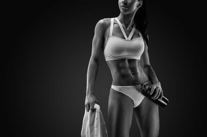 黑色背景中显示肌肉身材的健身美女
