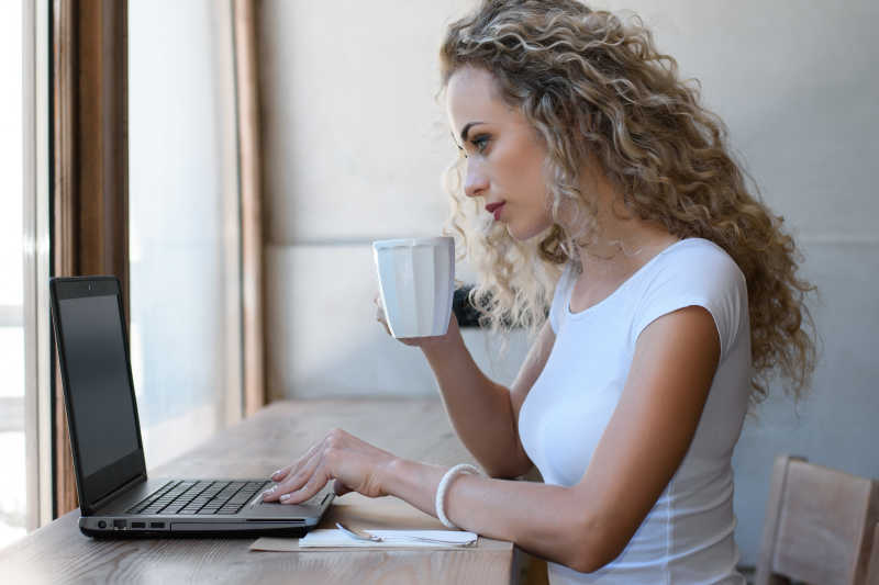 正在喝咖啡的美女观看电脑