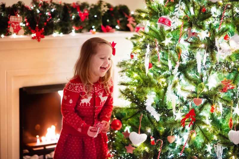装饰圣诞树的快乐的小女孩