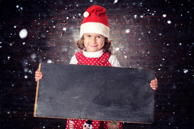 黑色星空背景下的圣诞节抱着黑板的小女孩
