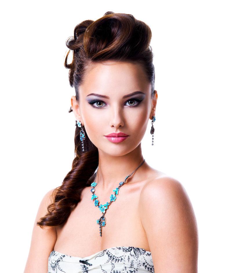 白色背景下画着精致妆容的带着蓝色珠宝首饰的美女