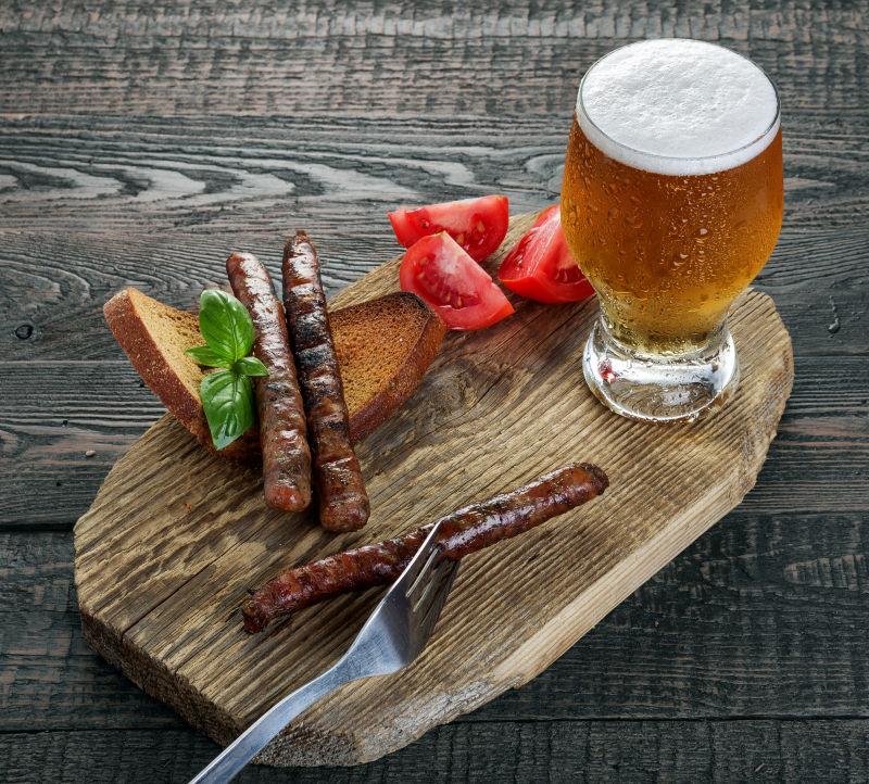 褐色木纹理桌上的木板上的烤香肠和啤酒