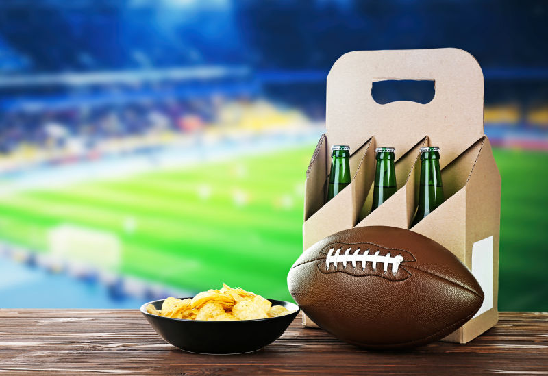足球场背景下的薯片啤酒和橄榄球