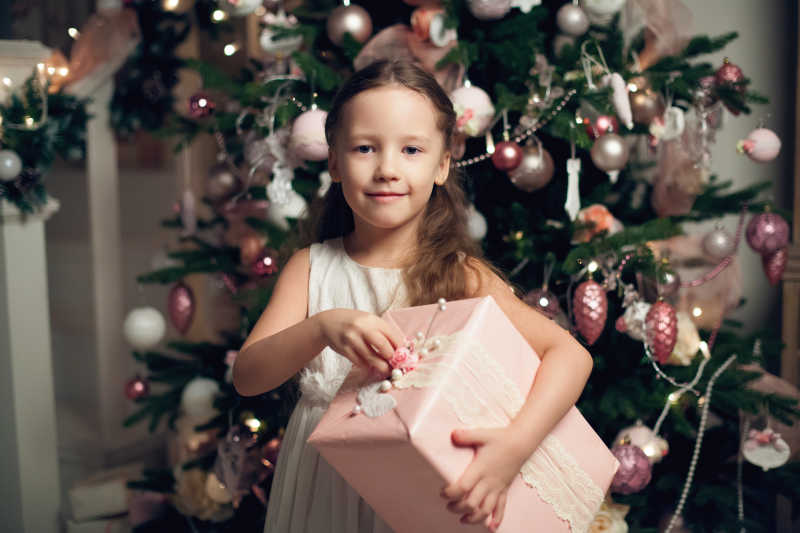 圣诞树下小女孩抱着她的圣诞礼物